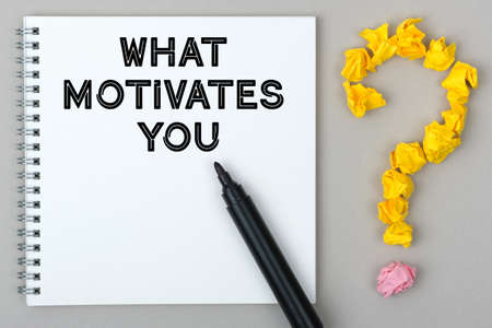Hand with marker writing: What Motivates You. Notepad and question mark.の写真素材