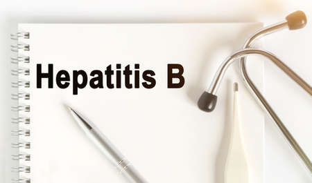 On the table are a stethoscope, a thermometer, a pen and a notebook with the inscription -Hepatitis B. The concept of medicine.の写真素材