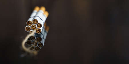 The concept of medicine is the fight against smoking. Cigarettes are twisted into a dynamite checker with a filament on a black reflective surface.の写真素材