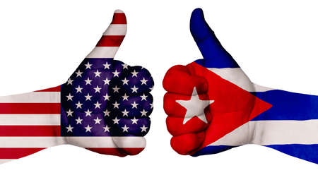The concept of strengthening the relationship of nations. Two hands are painted with flags of different countries, with a thumb raised up. Cuba and the USAの写真素材