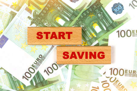 Business concept. Against the background of euro bills, the text is written on wooden blocks - start savingの写真素材