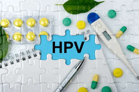 Double exposure. Puzzles with the image of tablets, a notebook, a thermometer and a pen with the inscription -HPV. The concept of medicine.の写真素材
