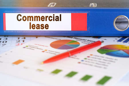 On the table are pie charts, a pen and a folder with the inscription - Commercial lease. Business and finance concept.の写真素材