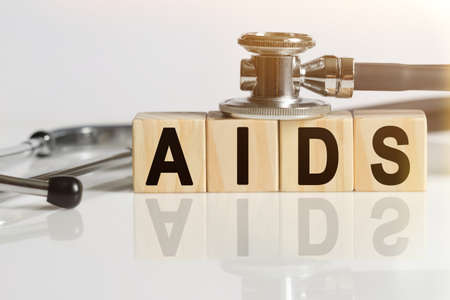 AIDS the word on wooden cubes, cubes stand on a reflective white surface, on cubes - a stethoscope. Medicine conceptの写真素材