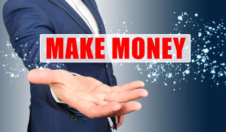 Finance and business concept. A businessman holds his hand, palm up, above the palm the inscription - MAKE MONEYの写真素材