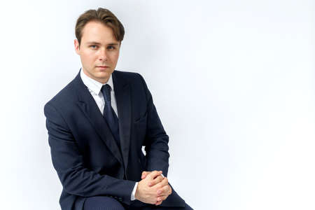 A portrait of a businessman in a blue suit who is clutching his hands. White background. Business and finance conceptの写真素材