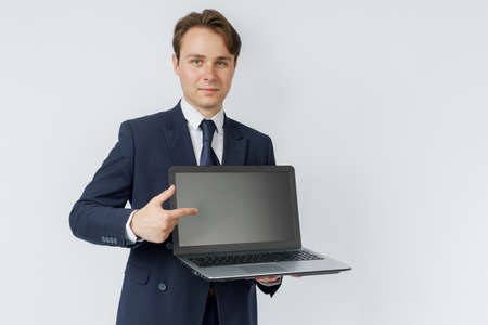 A businessman holds a laptop, the other hand shows the screen. White background. Business and finance conceptの写真素材