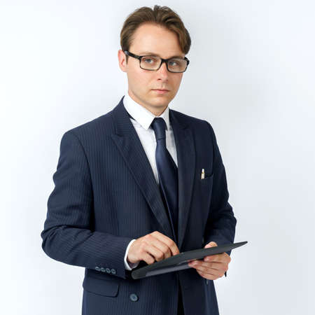 Portrait of a businessman in a blue suit holding an electronic tablet on a white background. Business and finance conceptの写真素材