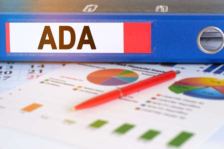 On the table are pie charts, a pen and a folder with the inscription - ADA. Americans with Disabilities Act. Business and finance concept.の写真素材