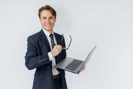 Portrait of a businessman who is holding a laptop and glasses. White background. Business and finance conceptの写真素材