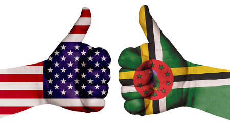 The concept of strengthening the relationship of nations. Two hands are painted with flags of different countries, with a thumb raised up. Dominica and the USAの写真素材
