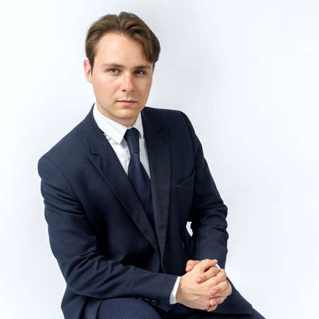 A portrait of a businessman in a blue suit who is clutching his hands. White background. Business and finance conceptの写真素材