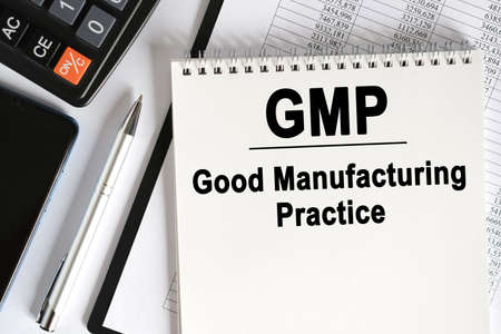 On the table lies a smartphone, a calculator and a notebook with the inscription- GMP. Good Manufacturing Practice. Business conceptの写真素材