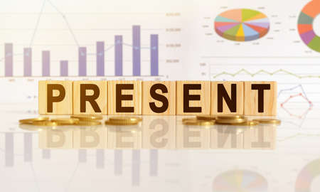 PRESENT the word on wooden cubes, cubes stand on a reflective surface, in the background is a business diagram. Business and finance conceptの写真素材