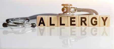 ALLERGY the word on wooden cubes, cubes stand on a reflective white surface, on cubes - a stethoscope. Medicine conceptの写真素材