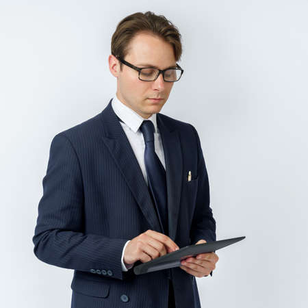 Portrait of a businessman in a blue suit holding an electronic tablet on a white background. Business and finance conceptの写真素材