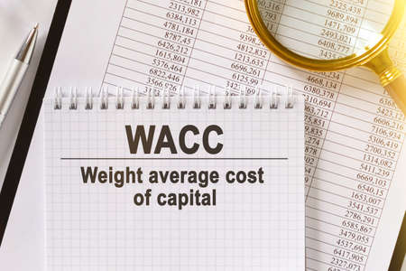 On the table are financial reports, a pen, a magnifying glass and a notebook with the inscription - WACC. Weight average cost of capital. Business and finance concept.の写真素材