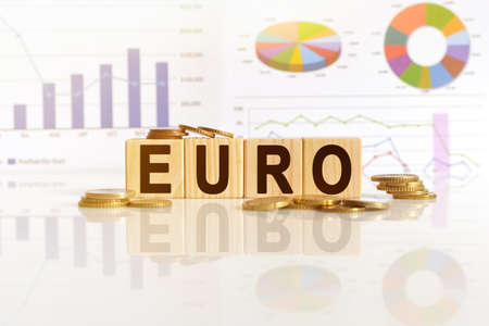 EURO the word on wooden cubes, cubes stand on a reflective surface, in the background is a business diagram. Business and finance conceptの写真素材