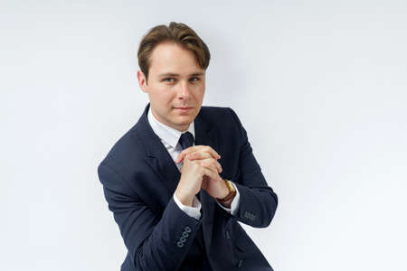 A portrait of a businessman in a blue suit who is clutching his hands. White background. Business and finance conceptの写真素材