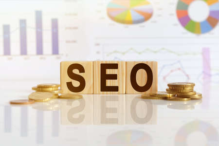 Search engine optimization. SEO the word on wooden cubes, cubes stand on a reflective surface, in the background is a business diagram. Business and finance conceptの写真素材