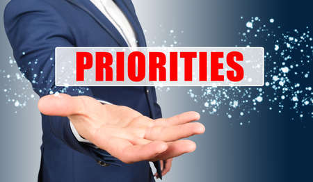 Finance and business concept. A businessman holds his hand, palm up, above the palm the inscription - PRIORITIESの写真素材