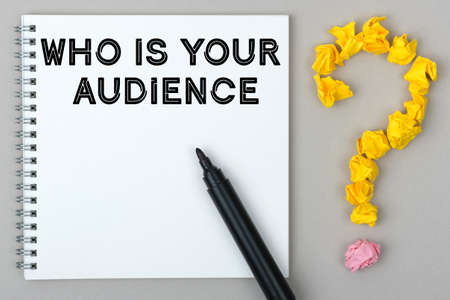Hand with marker writing: Who Is Your Audience. Notepad and question mark.の写真素材