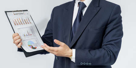 Businessman holds in his hands a tablet with reports. White background. No face visible. Business...