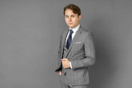 Portrait of a businessman in a suit looking at the camera. Gray background. Business and finance conceptの写真素材