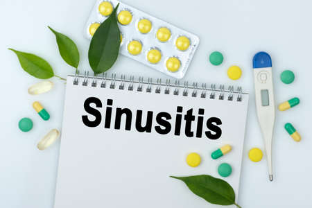 On the table are pills, a thermometer, leaves and a notebook with the inscription -Sinusitis. The concept of medicine.の写真素材