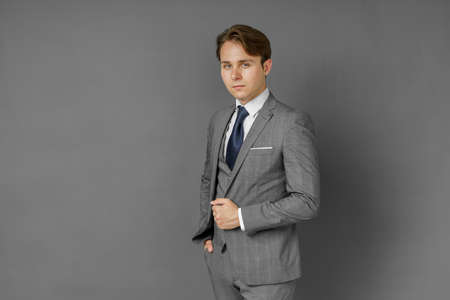 Portrait of a businessman in a suit looking at the camera. Gray background. Business and finance conceptの写真素材