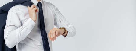 Portrait of a businessman in a blue suit who looks at his watch. No face visible. White background. Business and finance conceptの写真素材
