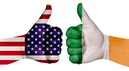 The concept of strengthening the relationship of nations. Two hands are painted with flags of different countries, with a thumb raised up. Ireland and the USAの写真素材