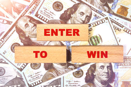 Business concept. Against the background of dollar bills, the text is written on wooden blocks - ENTER TO WINの写真素材