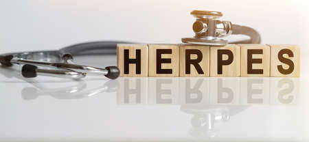 HERPES the word on wooden cubes, cubes stand on a reflective white surface, on cubes - a stethoscope. Medicine conceptの写真素材