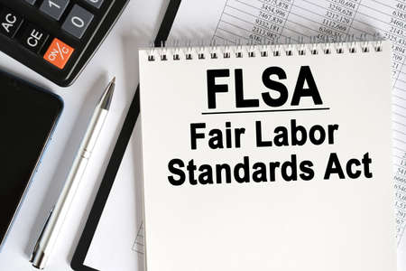 On the table lies a smartphone, a calculator and a notebook with the inscription- FLSA. Fair Labor Standards Act. Business conceptの写真素材