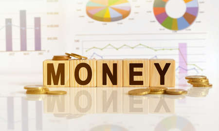 MONEY the word on wooden cubes, cubes stand on a reflective surface, in the background is a business diagram. Business and finance conceptの写真素材