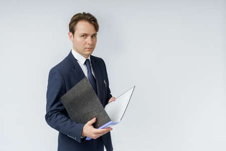 A businessman in a blue suit holds folders on a white background. Business and finance conceptの写真素材