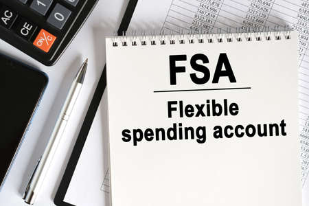 On the table lies a smartphone, a calculator and a notebook with the inscription- FSA. Flexible spending account. Business conceptの写真素材