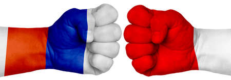 The concept of the struggle of peoples. Two hands are clenched into fists and are located opposite each other. Hands painted in the colors of the flags of the countries. Russia vs Polandの写真素材
