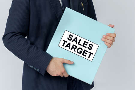 Business concept. A businessman holds a folder with documents, the text on the folder is - SALES TARGETの写真素材