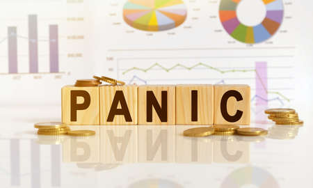 PANIC the word on wooden cubes, cubes stand on a reflective surface, in the background is a business diagram. Business and finance conceptの写真素材