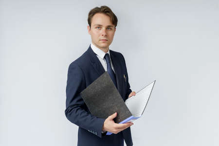 A businessman in a blue suit holds folders on a white background. Business and finance conceptの写真素材