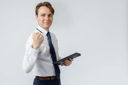 Portrait of a businessman raised his hand clenched into a fist, in the other hand an electronic tablet. White background. Business and finance conceptの写真素材