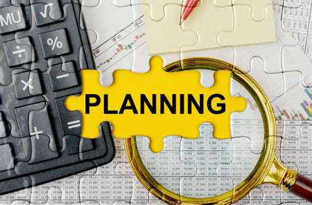 Business concept. Puzzle with a calculator, magnifying glasses and financial documents in the center inscription -PLANNINGの写真素材