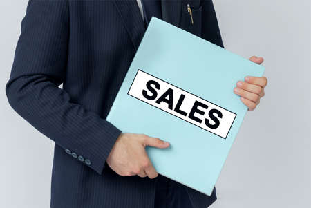 Business concept. A businessman holds a folder with documents, the text on the folder is - SALESの写真素材