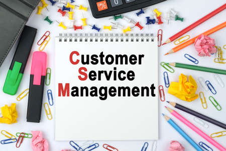 Business concept. On the table is a calculator, diary, markers, pencils and a notebook with the inscription - Customer Service Managementの写真素材