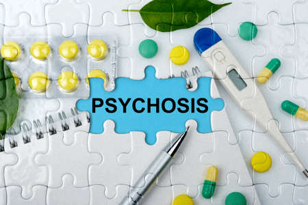 Double exposure. Puzzles with the image of tablets, a notebook, a thermometer and a pen with the inscription -PSYCHOSIS. The concept of medicine.の写真素材