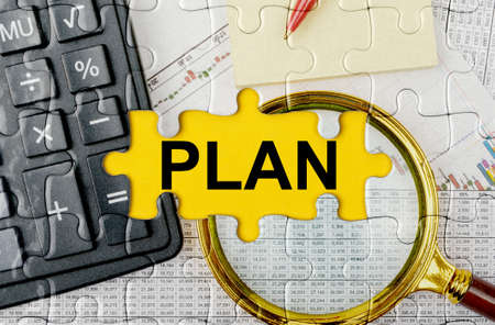 Business concept. Puzzle with a calculator, magnifying glasses and financial documents in the center inscription -PLANの写真素材