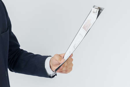 Businessman holds in his hands a tablet with reports. White background. No face visible. Business and finance conceptの写真素材