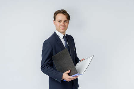 A businessman in a blue suit holds folders on a white background. Business and finance conceptの写真素材